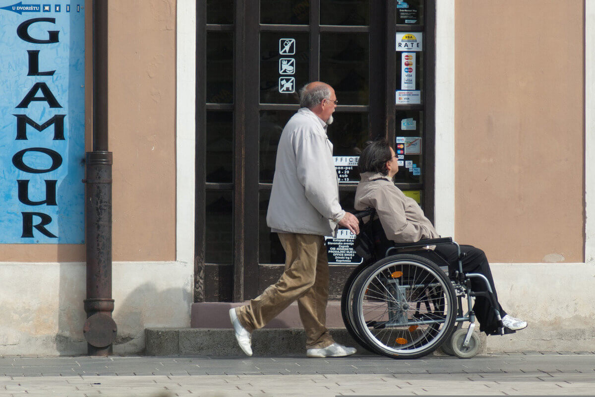 Man pushing woman in wheelchair